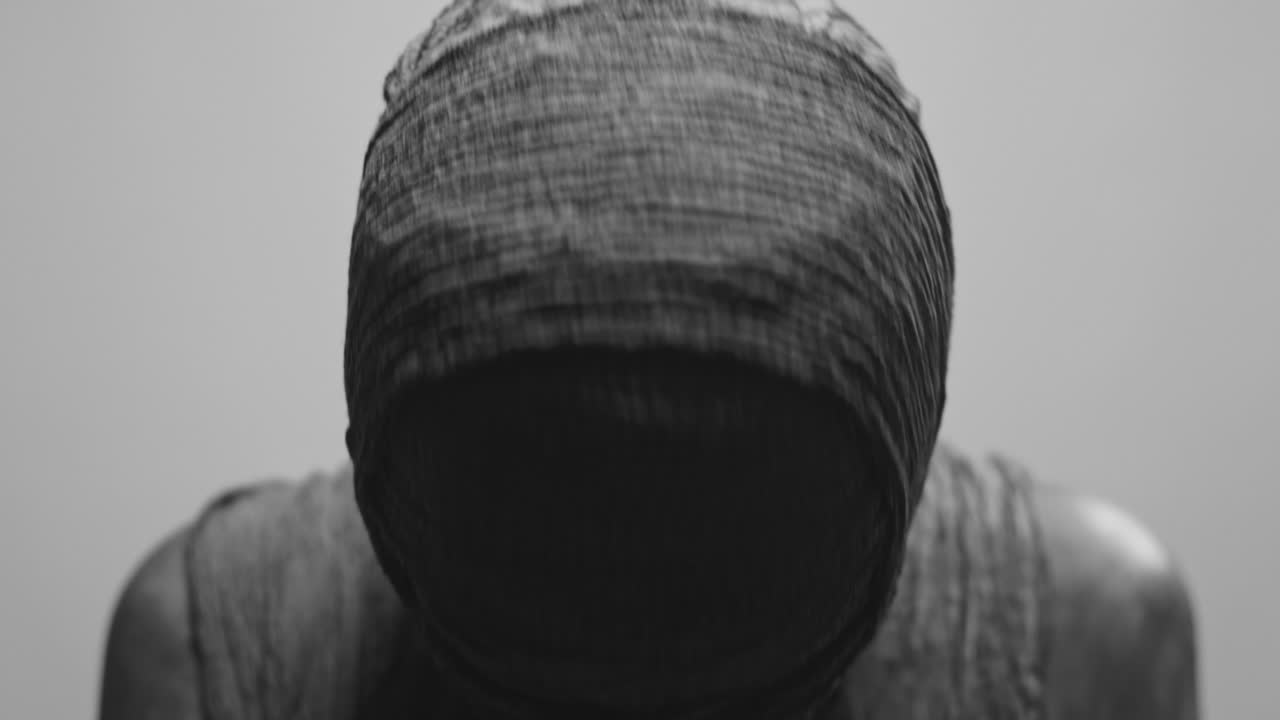 A mummy of a woman on a white backdrop rises her head