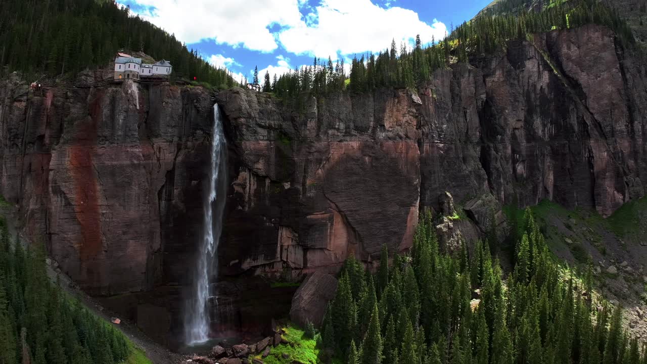 Telluride Bridal Veil Falls Waterfall Colorado powerplant house aerial drone down motion shade Aspen Trees Uncompahgre Forest summer green Box Canyon Black Bear Pass Road Rocky Mountains 4wd blue sky