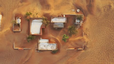 aerial view of an empty abandoned village and homes covered in desert sand near dubai