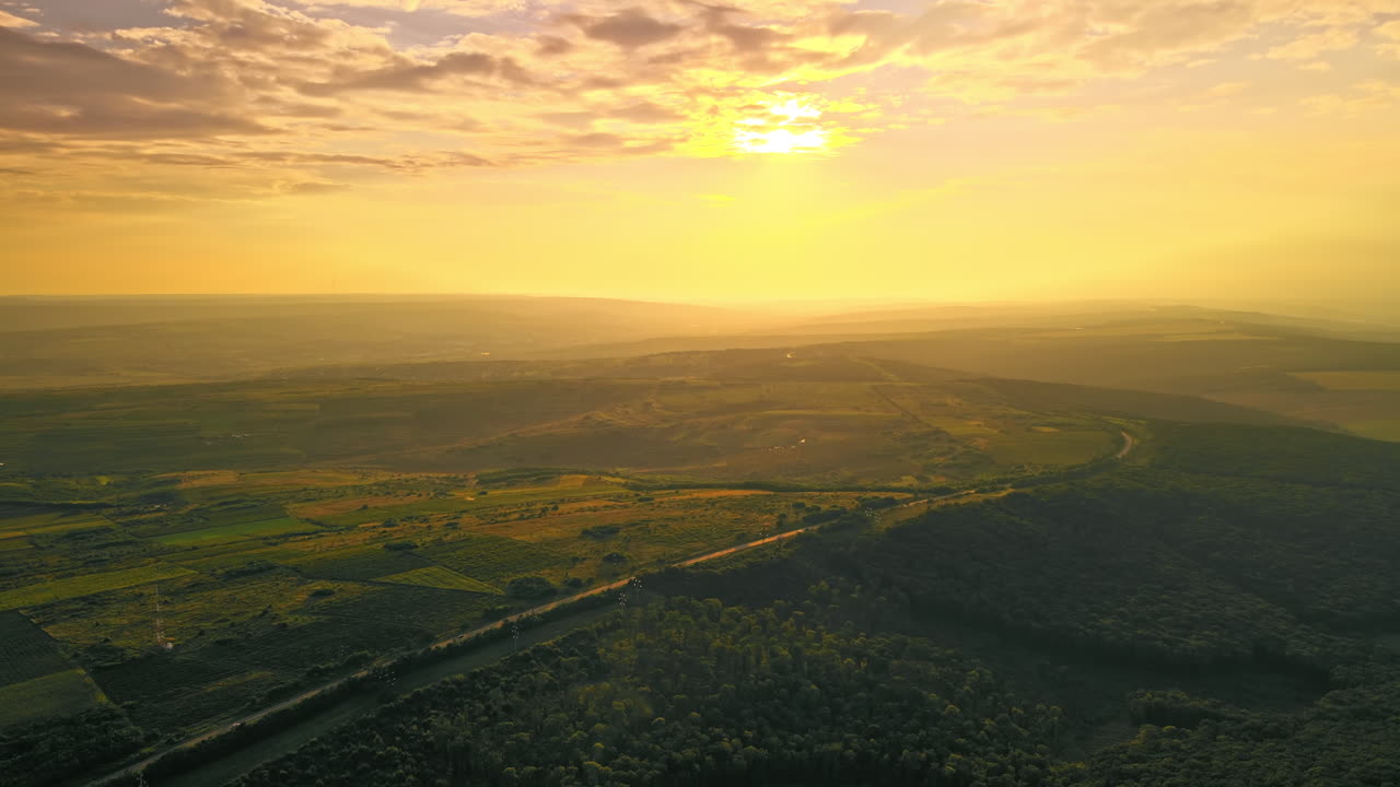 Aerial drone view of nature in Moldova at sunset. Highway, wide fields and hills, forest
