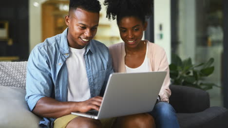 una pareja joven usando una computadora portátil juntos en casa