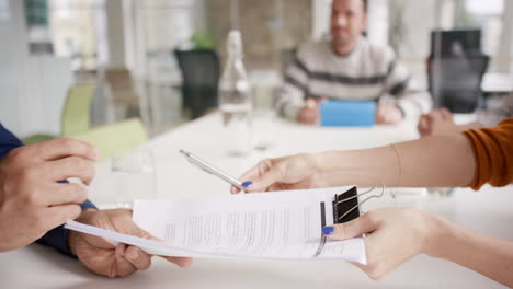 Female-executive-handing-over-partnership-agreement-Businessman-signing-contract-in-creative-modern-office-with-natural-light