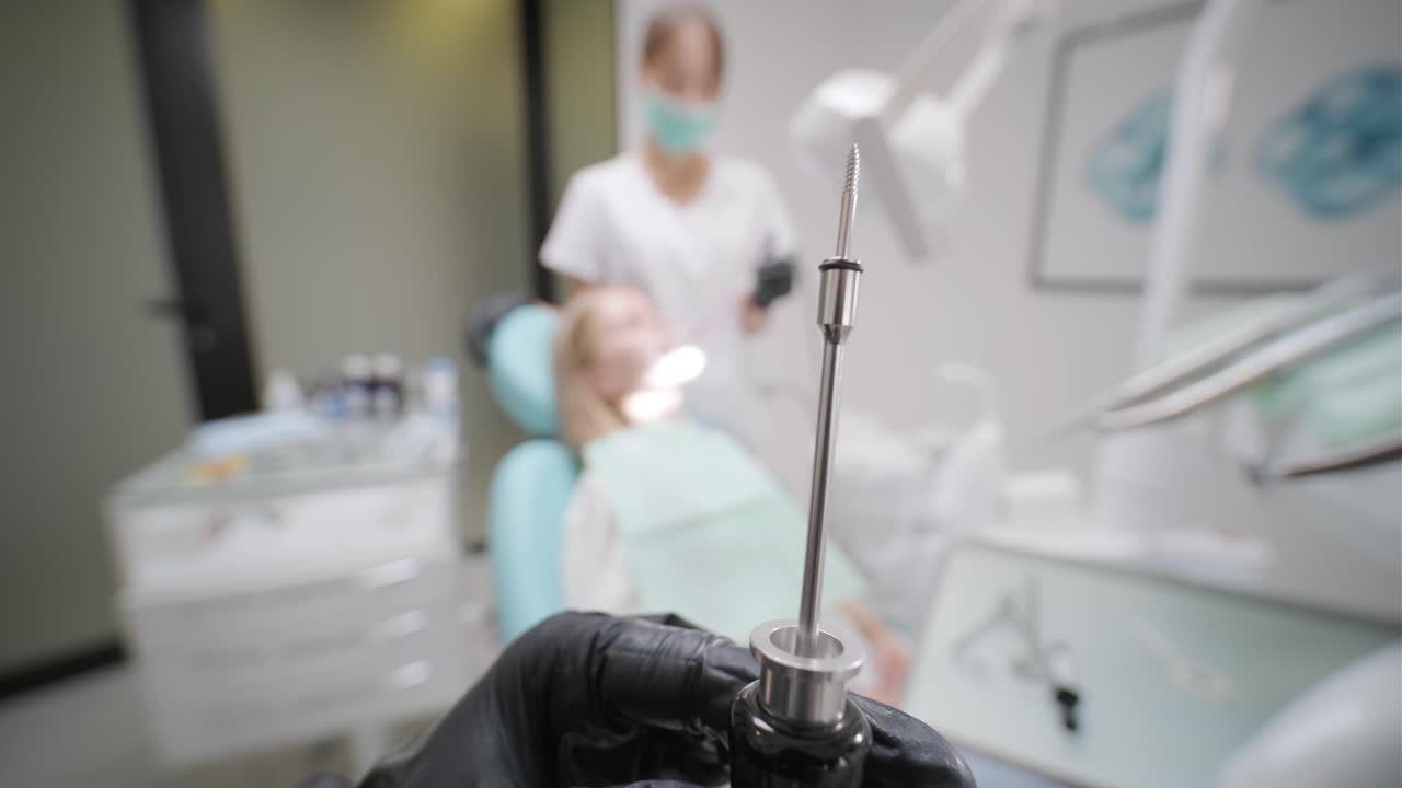 현대 치과 클리닉에서 환자의 입에 치과 임플란트를 설치하는 수술을 수행하는 주의 깊은 의사들의 클로즈업.