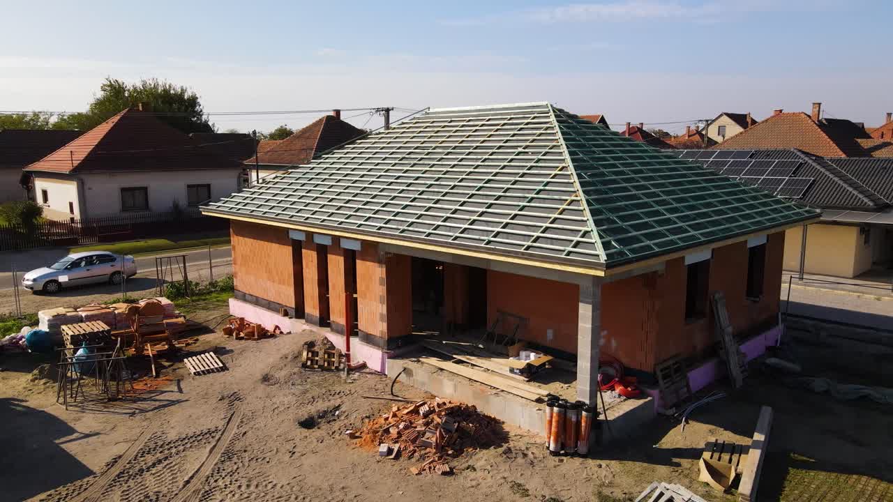New house under construction with brick walls and roof in strapping phase