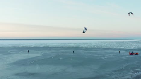 beautiful drone shot of kite boarding over frozen sea at dusk