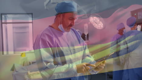 animation of flag of germany over biracial male surgeon using tablet in hospital