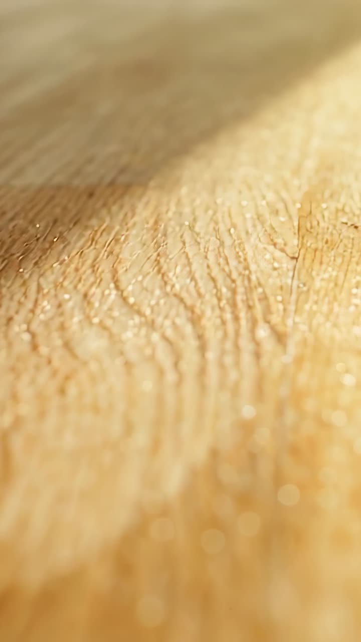 Vertikales Video: Sich verschiebendes Licht und die Kamera enthüllen die Maserung einer Holzplatte auf dem Tisch, Schatten und Staub glitzern.