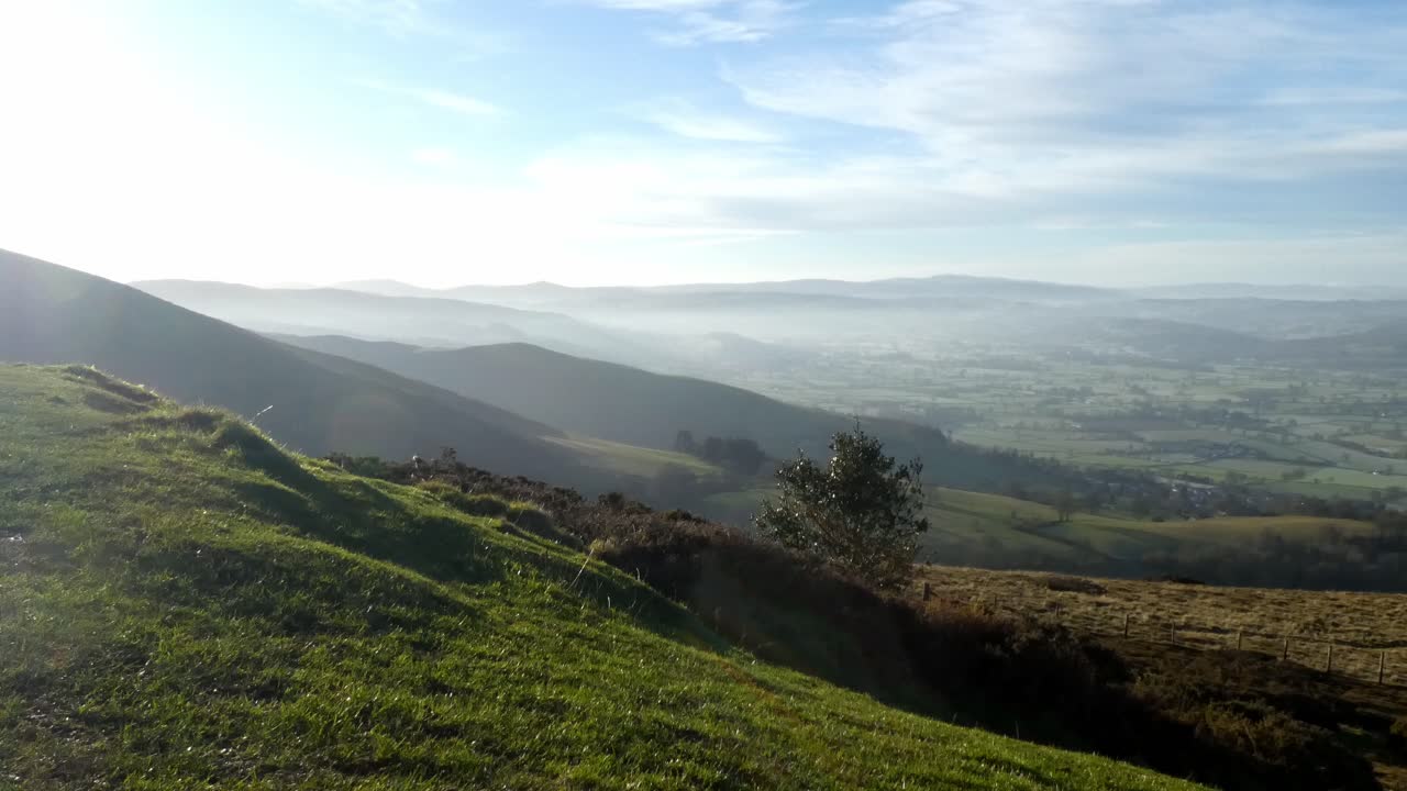 Distant misty layers of panoramic rural dreamlike mountain valley countryside at sunrise locked off shot