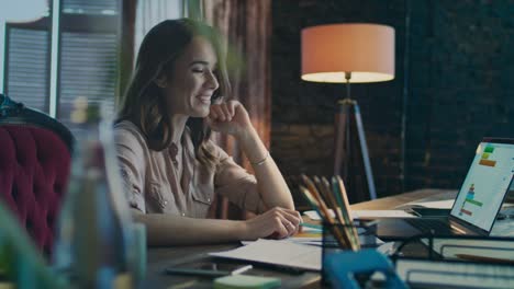 mujer de negocios feliz leyendo buenas noticias en una computadora portátil en la oficina de su casa