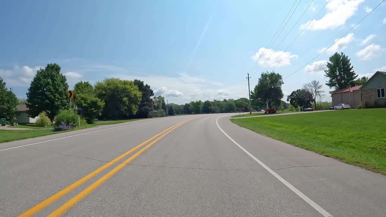 POV - Driving past workers with a trailer and generator preparing to lay cable in a rural subdivision; concepts of labor, cable and fiber optics
