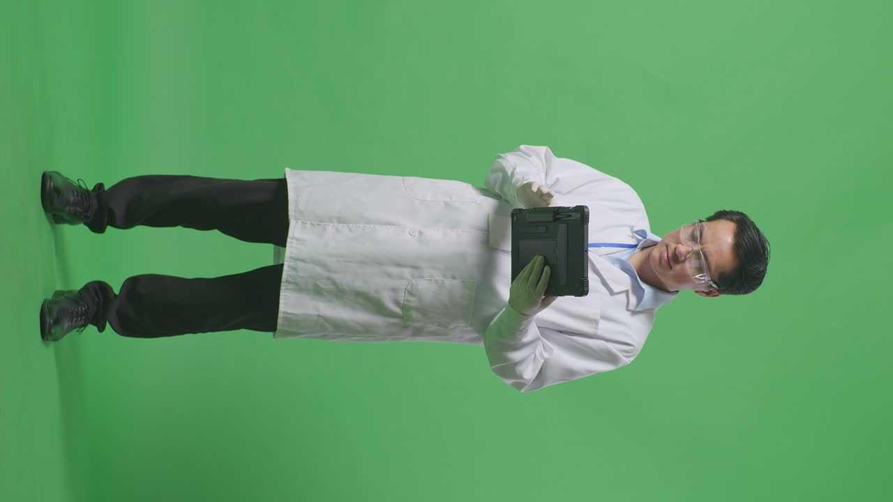 Full Body Of Smiling Asian Man Scientist Working On A Tablet While Standing On The Green Screen Background In The Laboratory