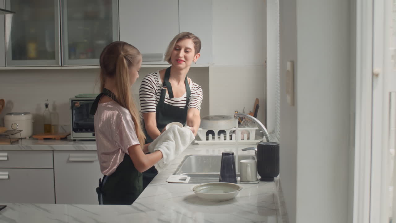 Girl Helping Mother with Washing Dishes at Kitchen