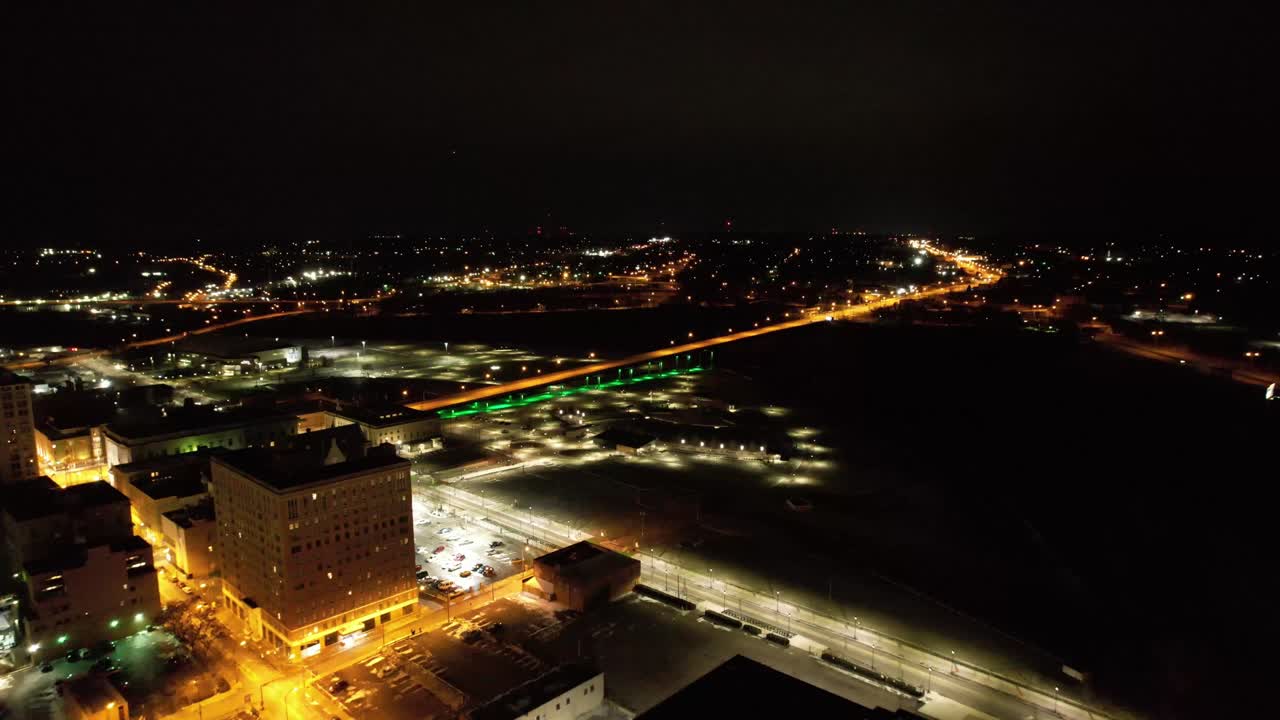 Downtown Youngstown illuminated at night with a glowing green-lit bridge and surrounding city lights captured in a sweeping aerial view.