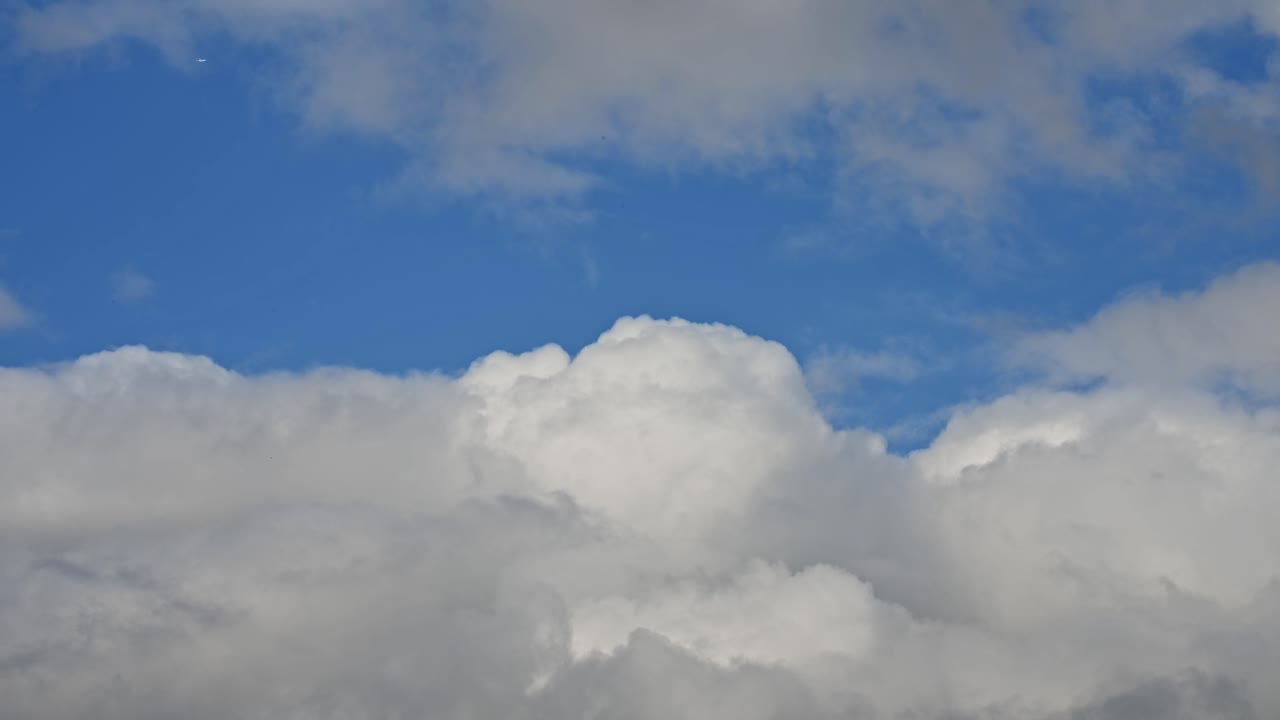 Time lapse of fluffy white clouds in blue sky. The contrast between the bright sky and the textured cloud layers creates a peaceful and natural atmosphere.