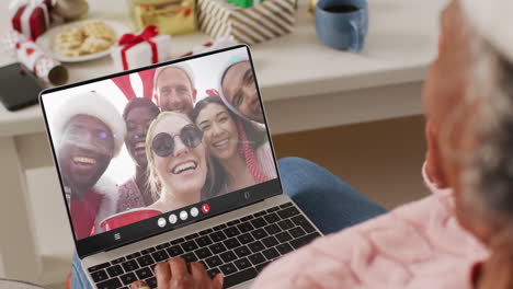 mujer afroamericana con sombrero de santa teniendo llamada de video portátil con amigos diversos felices