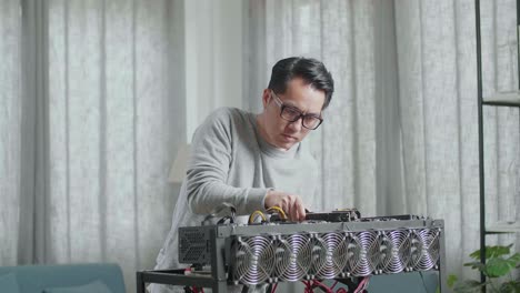 hombre asiático con gafas construye la plataforma de minería para la minería de criptomonedas