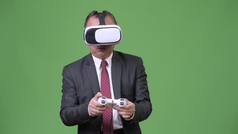 mature japanese businessman playing games against green background