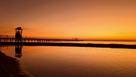 silueta de una mujer caminando por la playa durante una puesta de sol colorida