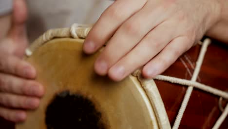 close up of hands of a man playing a drum.