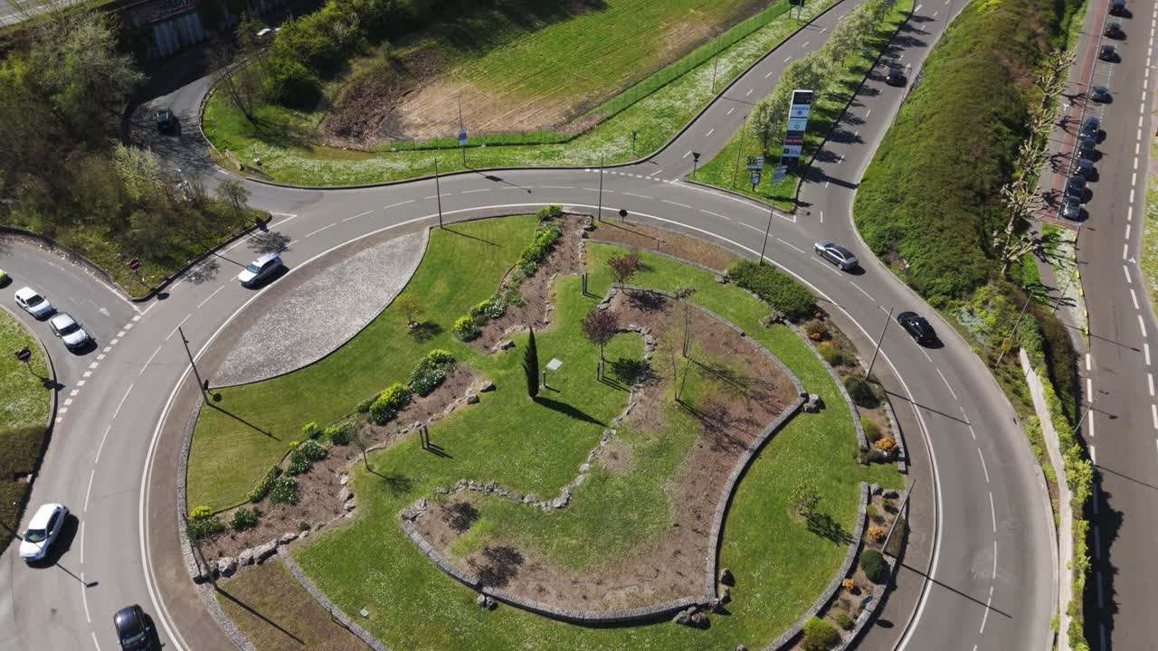 Aerial view of a busy roundabout with traffic and greenery in suburban Paris, shot on a sunny day - France