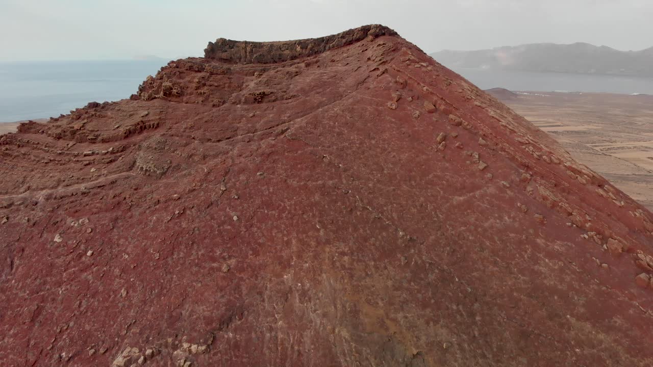 volando sobre un volcán rojo con un diminuto edificio blanco encima