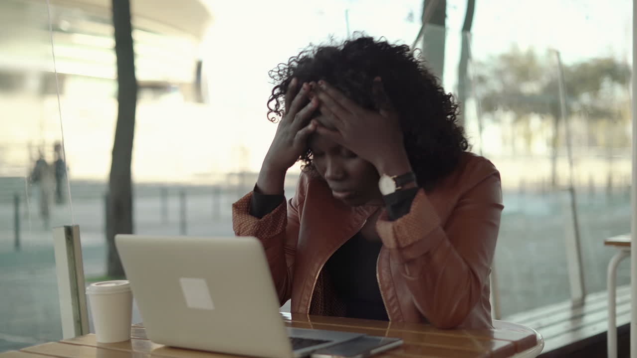 Serious female freelancer working with laptop computer in cafe