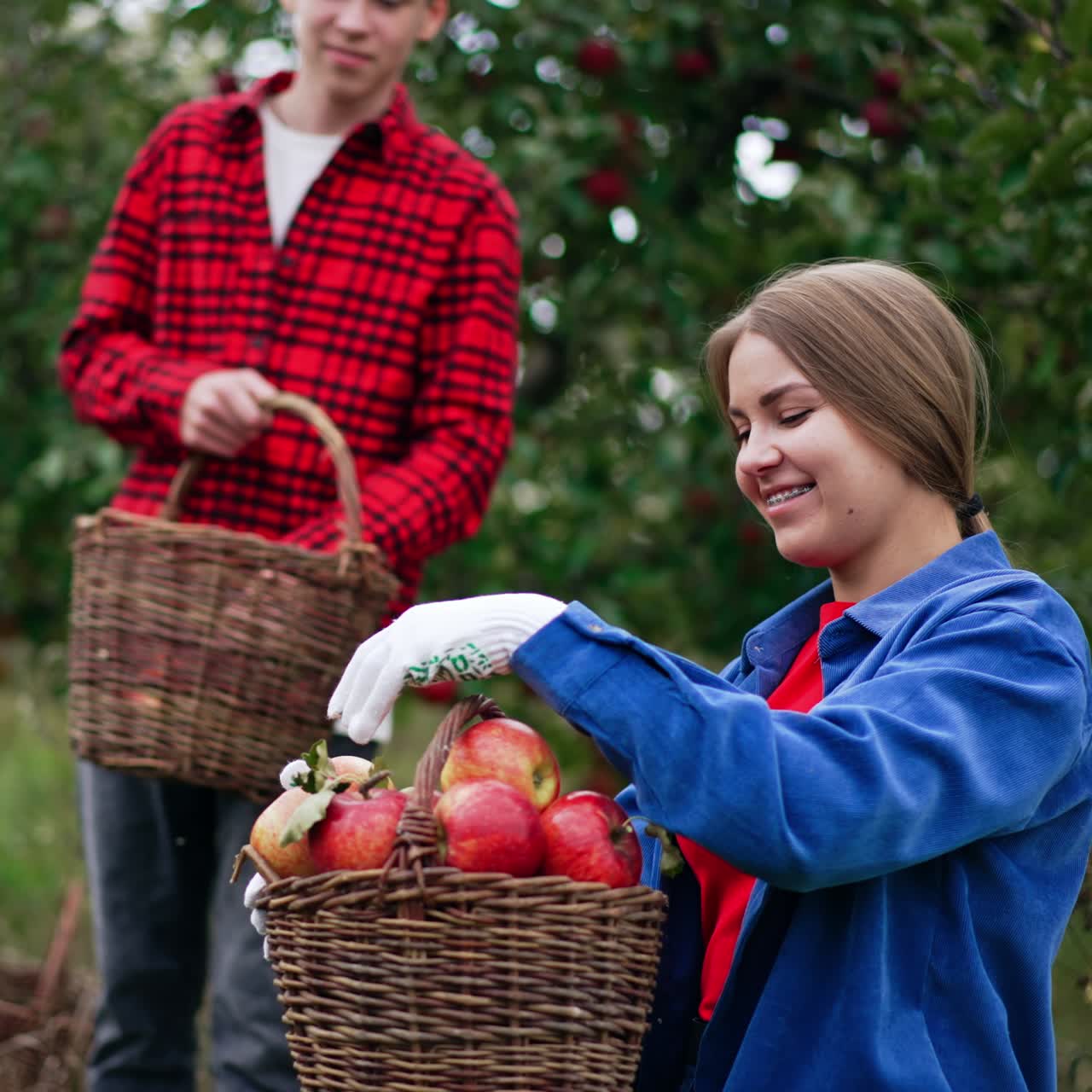People are happy about the harvest of apples in the garden. Young woman and teenage boy looking at fruit they've collected