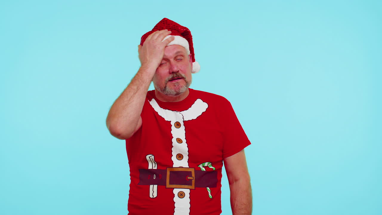 Upset man in Christmas red t-shirt making face palm gesture, feeling bored, disappointed, bad result