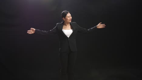 mujer de negocios en traje negro con los brazos extendidos