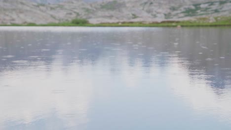 gentle rain falling on alpine lake with towering mountain peak in background