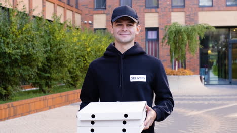 young man holding pizza boxes