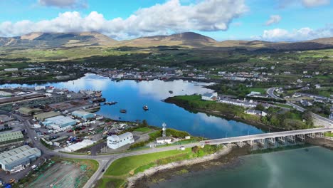 Puente-De-Drones-Al-Puerto-Pesquero-De-Castletownbere-Con-La-Ciudad-Y-Las-Montañas-De-West-Cork,-Irlanda,-Al-Fondo