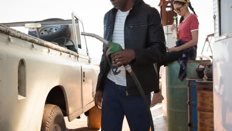 diverse man and woman filling up truck using fuel pump at petrol station