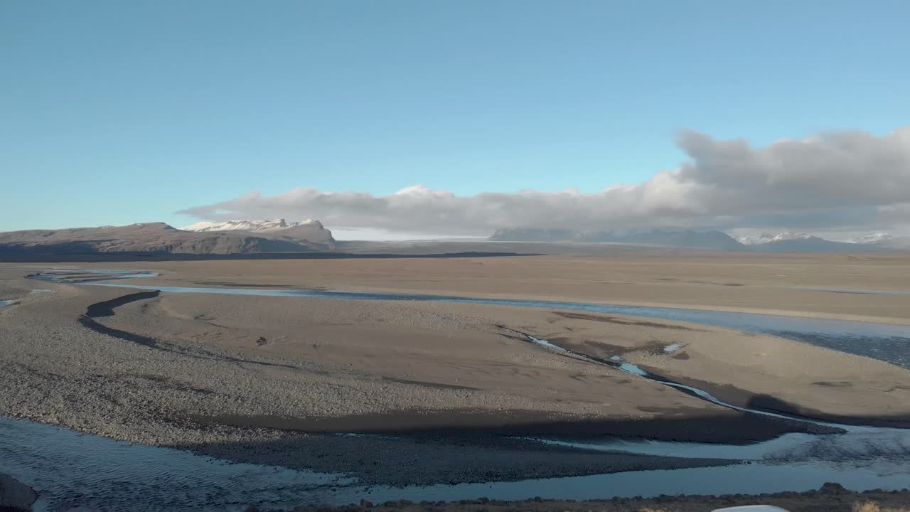 toma aérea cinematográfica de un automóvil estacionado a lo largo de un río glacial.