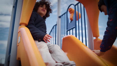 young boy climbing up a slide in a playground