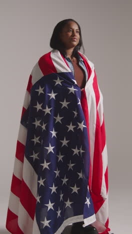 vertical video studio shot of woman wrapped in american flag celebrating 4th july independence day 1