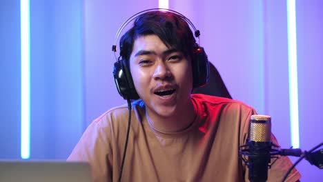asian man holding mobile phone and talking to camera while live stream