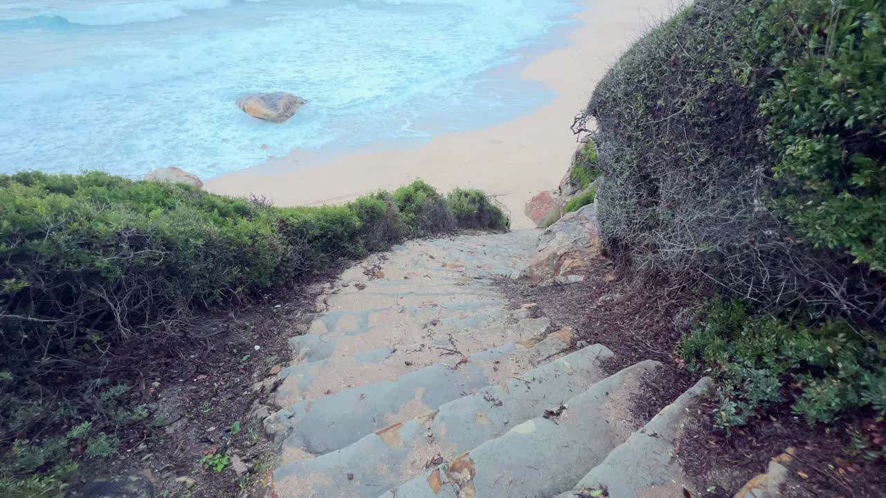 한적한 해변으로 이어지는 긴 자연 계단을 따라 촬영한 컷으로, 여정의 느낌을 불러일으킵니다.