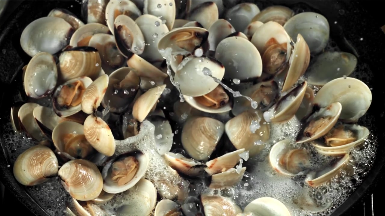 Nahaufnahme von Muscheln, die in kochendem Wasser garen und sich öffnen.