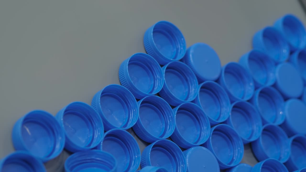 Close up: many blue plastic bottle caps moving on conveyor belt, production line