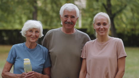 portrait of joyous senior couple and female fitness coach in park