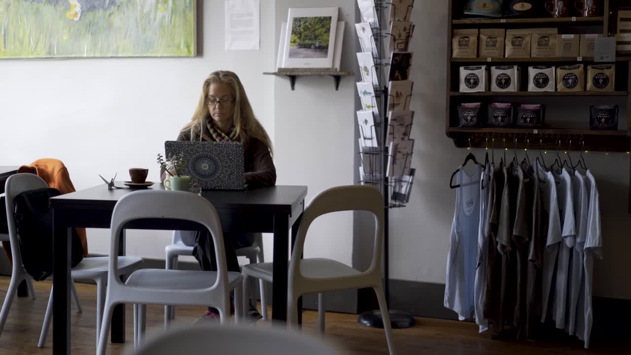 Kvinna som arbetar på en bärbar dator på ett kafé