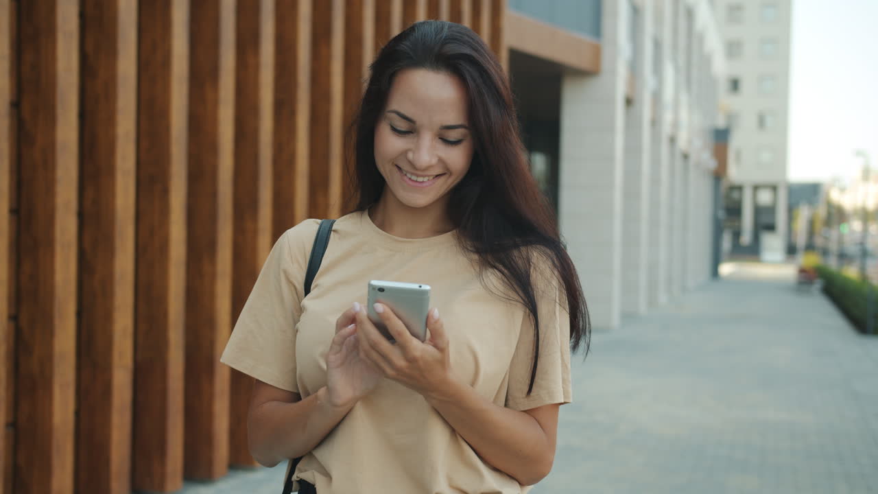 Donna che cammina e usa lo smartphone in città