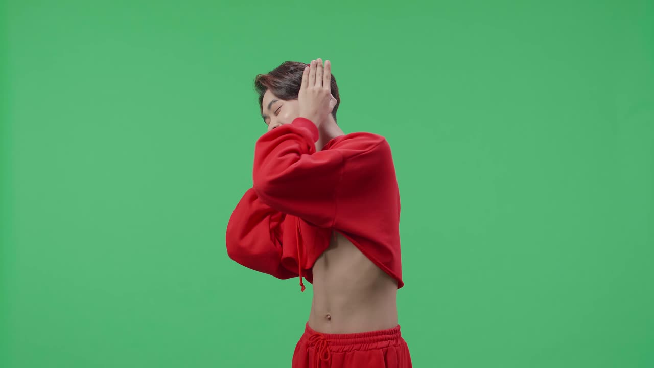 Side View Of Asian Transgender Male Listening To Music With Headphones And Dancing In The Green Screen Studio