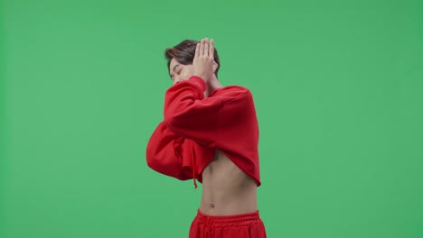 side view of asian transgender male listening to music with headphones and dancing in the green screen studio