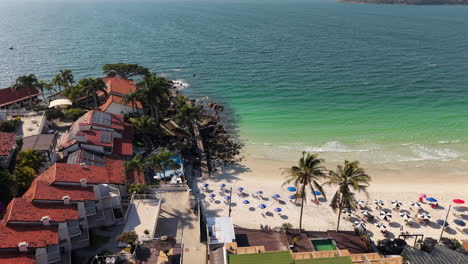 sunny bombinhas beach in santa catarina, brazil, with colorful umbrellas and small houses