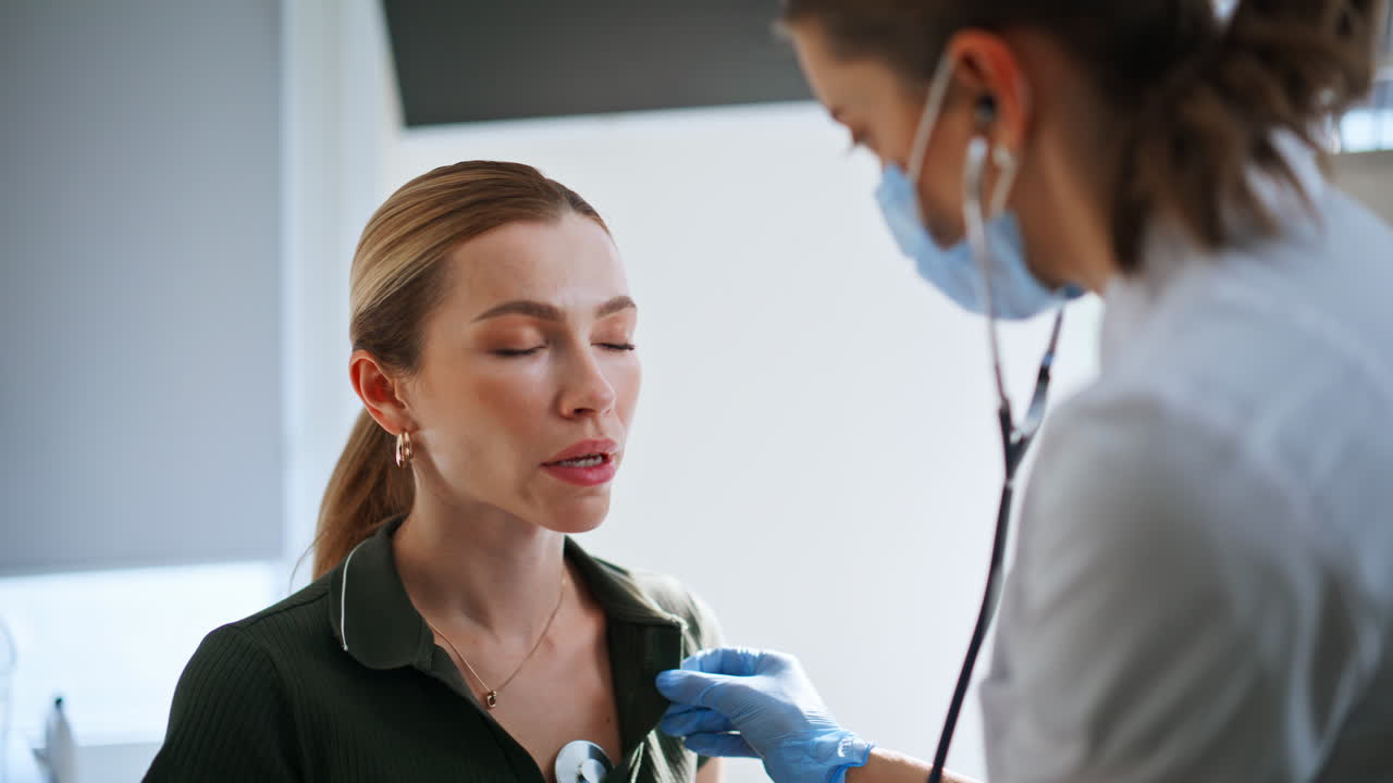 Lady doctor using stethoscope during health checkup. Sick woman visiting clinic