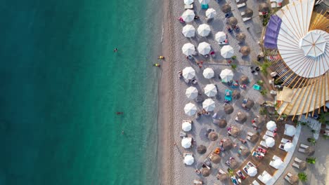 beach umbrella and bar, turquoise sea water washing shoreline of mediterranean coast in albania