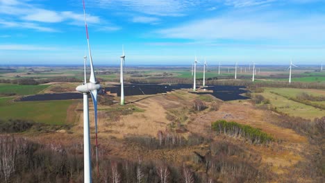 Aerial-shot-of-large-power-plant-of-solar-panels-in-Electrum-solar-park-and-wind-turbines-in-a-vast-field-on-a-sunny-day-in-Taurage,-Lithuania