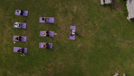 drone shot of teacher leading group of mature men and women in class at outdoor yoga retreat